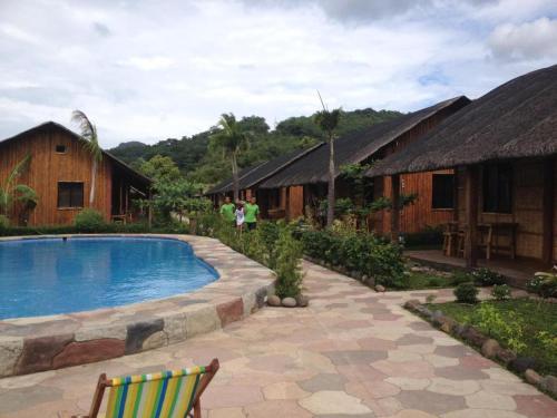 a resort with a swimming pool and some buildings at calayo beach resort in Calayo