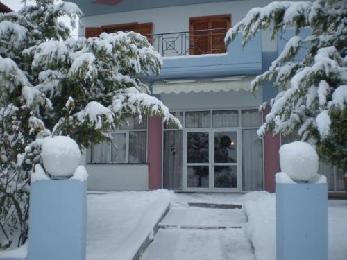 a house with snow covered trees in front of it at Hotel Limni in Agios Panteleimon