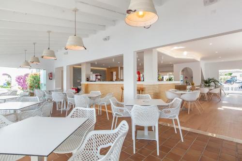 a restaurant with white tables and white chairs at Apartamentos Solecito in Port d'Alcudia