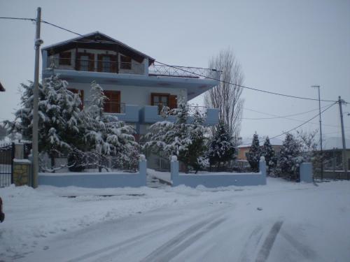 a house with snow covered trees in front of it at Hotel Limni in Agios Panteleimon