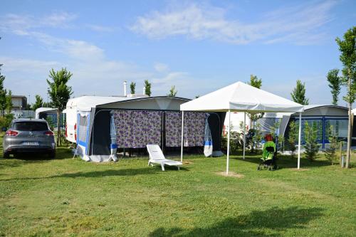 a group of tents and a car parked in a field at Villaggio Camping Adria in Casal Borsetti