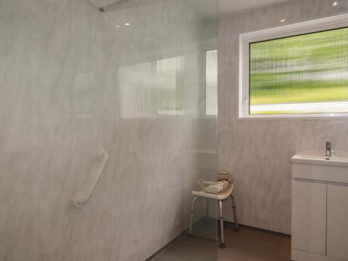 a bathroom with a shower and a sink and a window at 7 Chycoose Parc in Truro