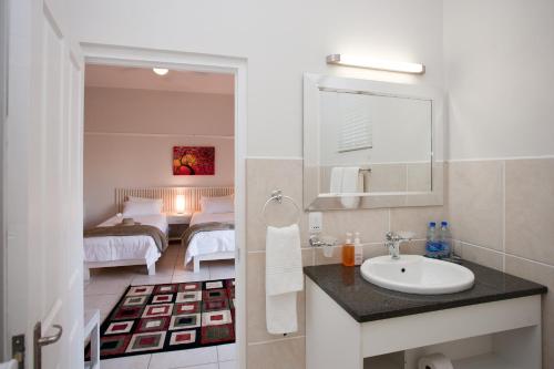 a bathroom with a sink and a bedroom at The Queen Of Calitzdorp in Calitzdorp