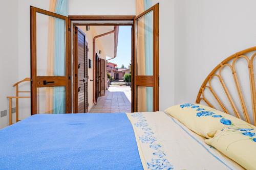a bedroom with a blue bed and an open door at Villetta Vespucci in Agrustos