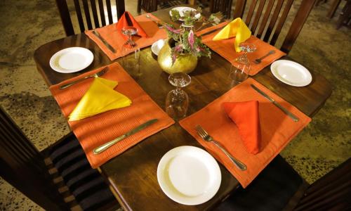 a wooden table with orange napkins and plates on it at Miracle Resorts & Villas in Polonnaruwa
