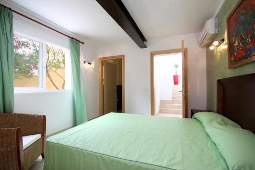 a bedroom with a green bed and a window at Can Medina in Pollença