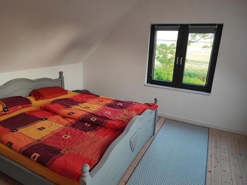 a bedroom with a bed with a red comforter and a window at Haus am Deich in Norden