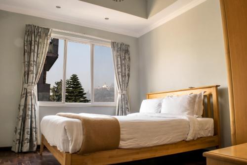 a bedroom with a large bed with a window at Retreat Serviced Apartment in Kathmandu