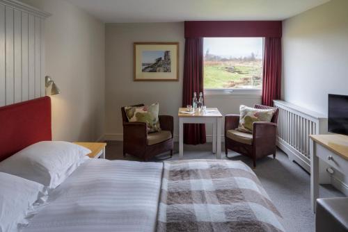 ein Hotelzimmer mit einem Bett, einem Tisch und einem Fenster in der Unterkunft Westmorland Hotel Tebay in Tebay