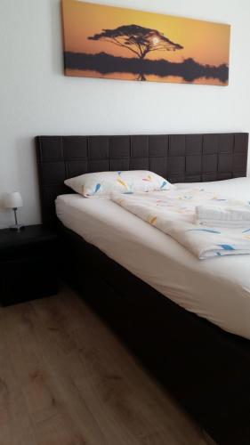 a bed in a bedroom with a picture of a tree at Hotel Ackermann in Riedstadt