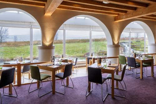 a restaurant with tables and chairs and large windows at Westmorland Hotel Tebay in Tebay