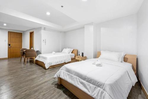 a hotel room with two beds and a table and chairs at Espacio Hotel in Manila