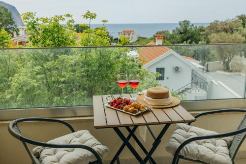 a table with two glasses of wine and a bowl of fruit at Apartments Via Mare in Petrovac na Moru