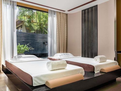 two beds in a room with a large window at V Villas Hua Hin - MGallery Collection in Hua Hin