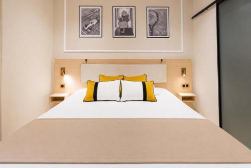 a bedroom with a large white bed with yellow pillows at Hôtel de France in Monte Carlo