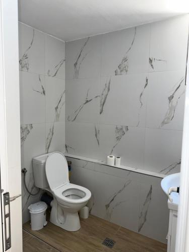 a white bathroom with a toilet and a sink at Adela's Saranda Central Apartment in Sarandë