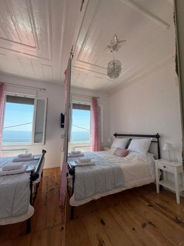 a bedroom with a bed and two windows with the ocean at Villa Rosa in Plomari