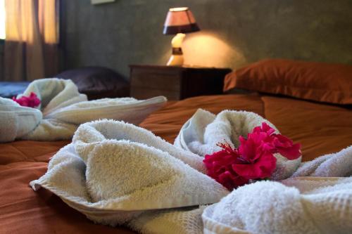 a bed with white towels and red flowers on it at Casa Drake Lodge in Drake