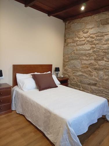a bedroom with a large bed with a stone wall at Casa da Eira in Lobios