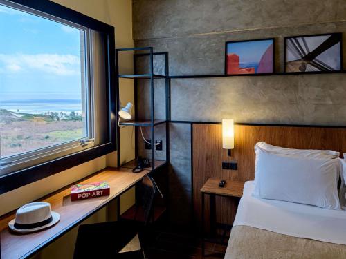 a bedroom with a bed and a desk with a window at ibis Sao Luis in São Luís