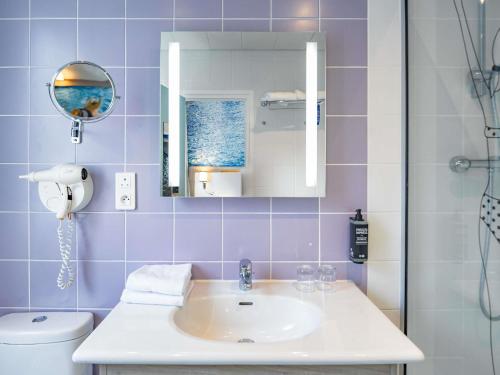 a bathroom with a sink and a mirror and a toilet at ibis Styles Calais Centre in Calais