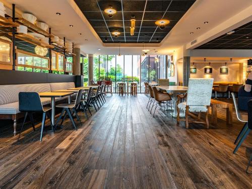 a restaurant with wooden floors and tables and chairs at Novotel Suites Reims Centre in Reims