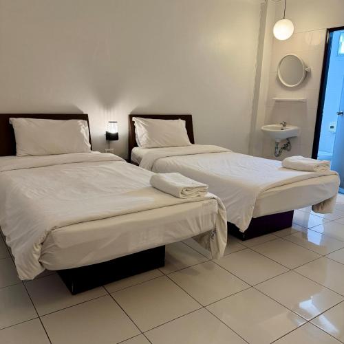 two beds in a room with white sheets and pillows at The Northeast Hotel in Si Sa Ket