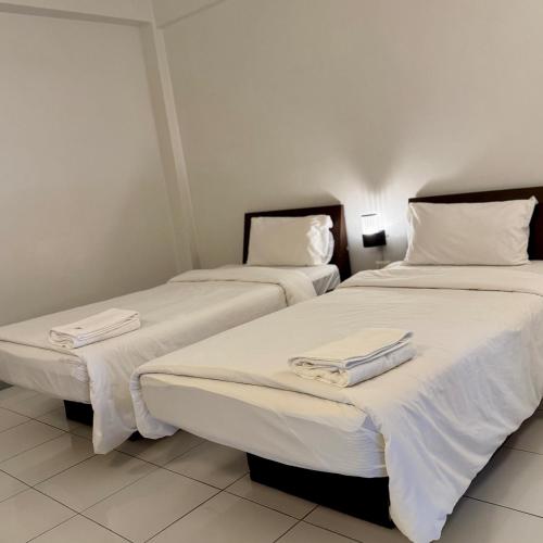 two beds in a hotel room with towels on them at The Northeast Hotel in Si Sa Ket