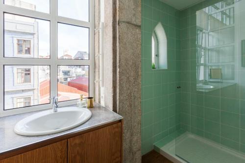 ein Bad mit einem Waschbecken, einer Dusche und einem Fenster in der Unterkunft Abbey Apartments City Center in Porto