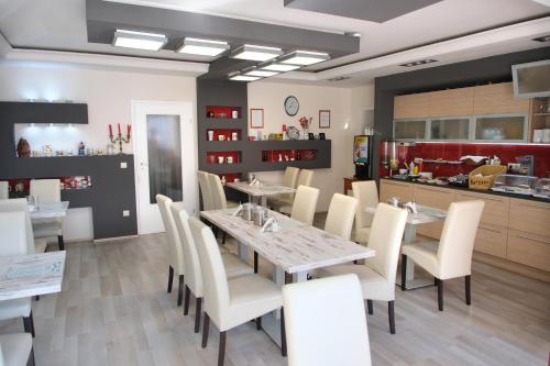a dining room with a table and white chairs at Szieszta Panzió in Sárvár