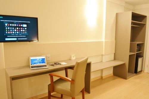 Habitación con escritorio, ordenador portátil y TV. en Villa Premium Hotel, en Erechim