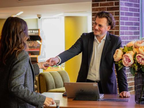 a man shaking hands with a woman at a table at Novotel Lyon Centre-Confluence Bord de Saone in Lyon
