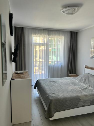 a bedroom with a bed and a tv and a window at Familienapartment am Strand in Primorsko in Primorsko