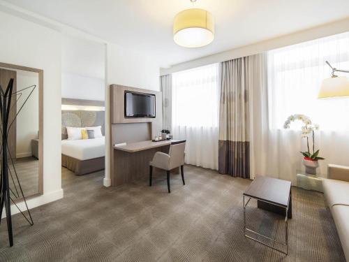 a hotel room with a bed and a living room at Novotel SPA Rennes Centre Gare in Rennes