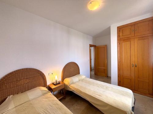 a room with two beds and a table with a lamp at Los Enebros in Cartaya