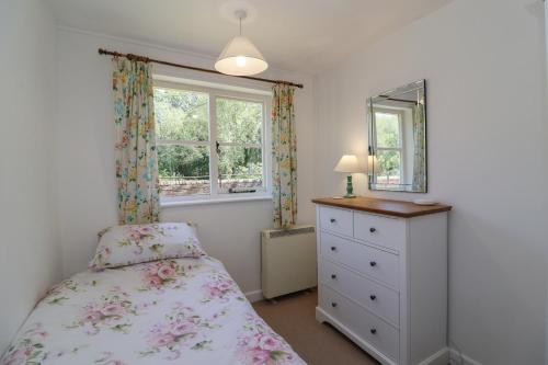 a bedroom with a bed and a dresser and a mirror at Walk Farm Cottage in Gloucester