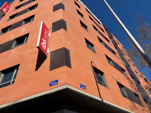 a tall red brick building with a sign on it at Ibis Madrid Centro las Ventas in Madrid