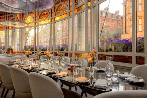 a dining room with a long table and white chairs at The Connaught, Maybourne in London