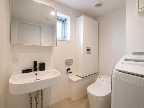 a white bathroom with a sink and a toilet at The Aoca Tokyo Kaminoge in Tokyo