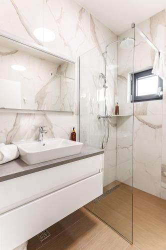 a white bathroom with a sink and a shower at Stella Maris Deluxe in Podstrana