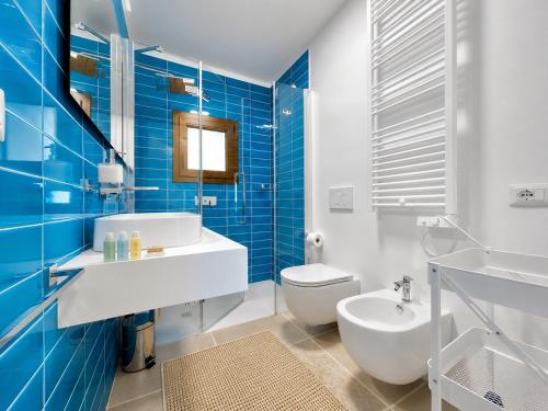 a bathroom with a sink and a toilet and blue tiles at Renew Terrace RB Two Bedroom 50m from the Beach in Baja Sardinia