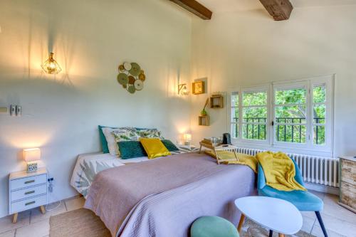 a bedroom with a bed and two chairs and a window at Chambre D'hôtes Le Moulin in Balaruc-le-Vieux