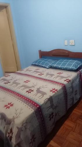 a bedroom with a bed with a blanket on it at Hotel Flamingos in Santos
