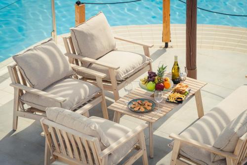 a patio with two chairs and a table with a bowl of fruit at Kamari Beach Hotel in Potos