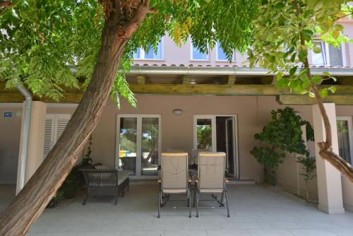 a patio with a table and chairs under a tree at Rab Barbat Villas 4 stars 300 sea in Barbat na Rabu