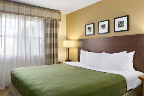 a hotel room with a bed with a green bedspread at Country Inn & Suites by Radisson, Rochester South, MN in Rochester