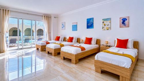 a bedroom with three beds and a large window at Stunning villa w Private pool TT table Sleeps 14 in St. Julianʼs
