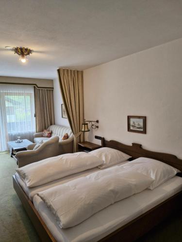 a bedroom with two beds and a living room at Hotel Garni Tonihof in Eschenlohe