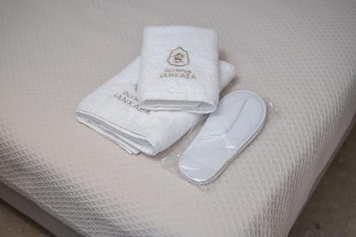 a pair of towels and a pair of shoes on a bed at Olympus Jankaea in Paralia Katerinis