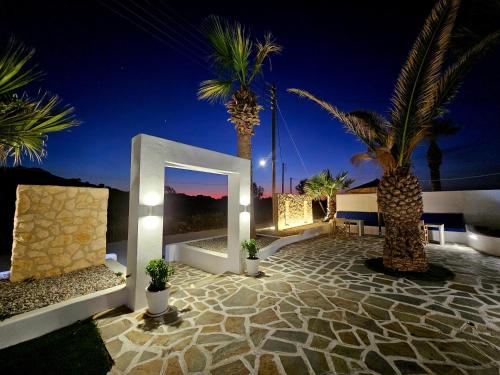 a courtyard with palm trees and lights at night at Coralli Beach Apartments in Mikri Vigla